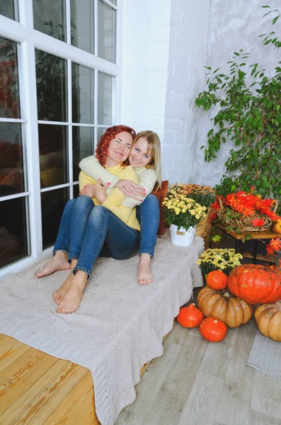 İki hoş genç kadın, kız kardeş, sıcak kazaklı arkadaşlar rahat bir evde yatakta oturmuş gülüyor, eğleniyorlar. Sonbahar süslemeleri, portakal yaprakları, çiçekler, balkabakları olan ev.. 