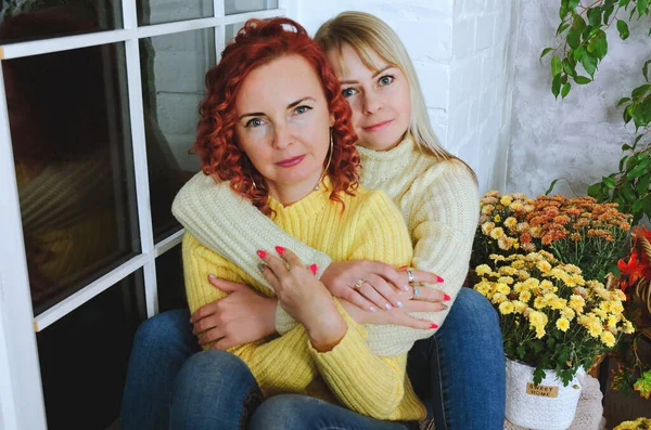 İki hoş genç kadın, kız kardeş, sıcak kazaklı arkadaşlar rahat bir evde yatakta oturmuş gülüyor, eğleniyorlar. Sonbahar süslemeleri, portakal yaprakları, çiçekler, balkabakları olan ev.. 