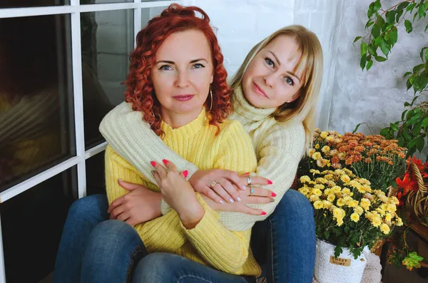 İki hoş genç kadın, kız kardeş, sıcak kazaklı arkadaşlar rahat bir evde yatakta oturmuş gülüyor, eğleniyorlar. Sonbahar süslemeleri, portakal yaprakları, çiçekler, balkabakları olan ev.. 