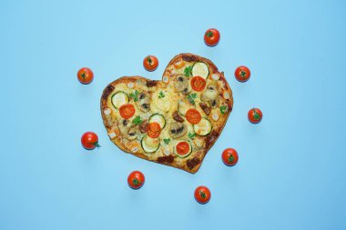 Arka planda Sevgililer Günü için domatesli, sebzeli ve peynirli kalp şeklinde pizza. Romantik aşkın yaratıcı yemek konsepti. Üst manzara, düz uzanma.