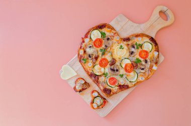 Arka planda Sevgililer Günü için domatesli, sebzeli ve peynirli kalp şeklinde pizza. Romantik aşkın yaratıcı yemek konsepti. Üst manzara, düz uzanma.