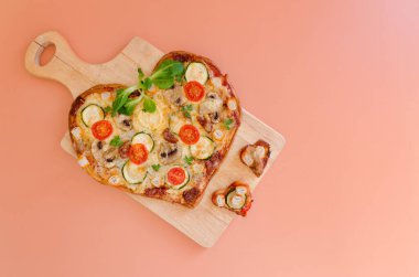 Arka planda Sevgililer Günü için domatesli, sebzeli ve peynirli kalp şeklinde pizza. Romantik aşkın yaratıcı yemek konsepti. Üst manzara, düz uzanma.