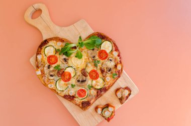 Arka planda Sevgililer Günü için domatesli, sebzeli ve peynirli kalp şeklinde pizza. Romantik aşkın yaratıcı yemek konsepti. Üst manzara, düz uzanma.