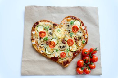 Arka planda Sevgililer Günü için domatesli, sebzeli ve peynirli kalp şeklinde pizza. Romantik aşkın yaratıcı yemek konsepti. Üst manzara, düz uzanma.