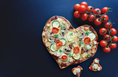 Arka planda Sevgililer Günü için domatesli, sebzeli ve peynirli kalp şeklinde pizza. Romantik aşkın yaratıcı yemek konsepti. Üst manzara, düz uzanma.