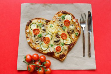 Arka planda Sevgililer Günü için domatesli, sebzeli ve peynirli kalp şeklinde pizza. Romantik aşkın yaratıcı yemek konsepti. Üst manzara, düz uzanma.