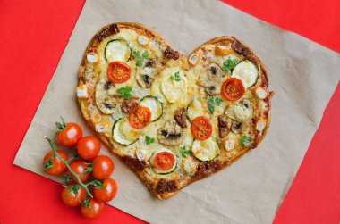 Arka planda Sevgililer Günü için domatesli, sebzeli ve peynirli kalp şeklinde pizza. Romantik aşkın yaratıcı yemek konsepti. Üst manzara, düz uzanma.