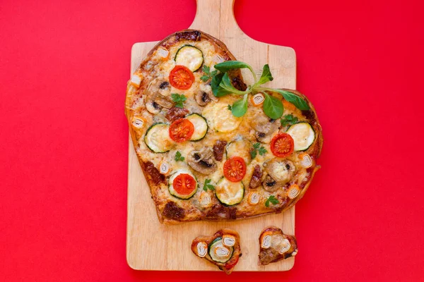 Arka planda Sevgililer Günü için domatesli, sebzeli ve peynirli kalp şeklinde pizza. Romantik aşkın yaratıcı yemek konsepti. Üst manzara, düz uzanma.