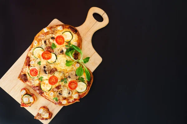 Heart shaped pizza with tomatoes, vegetables and cheese for Valentine's Day on background. Creative food concept of romantic love. Top view, flat lay.