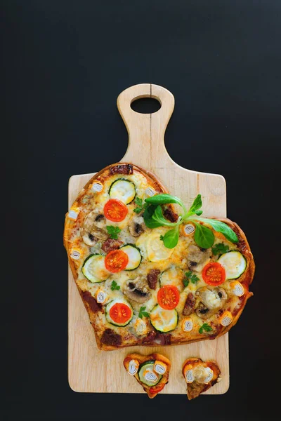 Arka planda Sevgililer Günü için domatesli, sebzeli ve peynirli kalp şeklinde pizza. Romantik aşkın yaratıcı yemek konsepti. Üst manzara, düz uzanma.