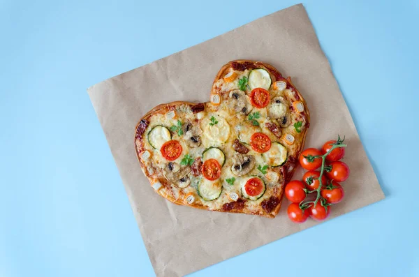 Arka planda Sevgililer Günü için domatesli, sebzeli ve peynirli kalp şeklinde pizza. Romantik aşkın yaratıcı yemek konsepti. Üst manzara, düz uzanma.