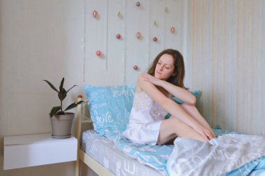 Genç ve mutlu bir kadın, gelin pijamalarıyla yatakta uzanıyor, rahat bir evde bornoz giyiyor. İçme suyu. Rahat ol. Sağlıklı bir yaşam tarzı. Sabah ritüelleri. 