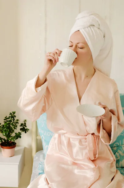 수건을 머리에 집에서 차림으로 침대에 커피를 마시고 아름다움의 일상사 로열티 프리 스톡 사진