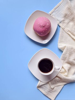 Bir fincan sıcak kahve ve mavi arka planda tatlı çöreklerle dolu bir sabah. Bir buket lale. Üst görünüm, kopyalama alanı, modelleme. Düz yatıyordu. Yiyecek ve içecekler. Bahar tatili. 