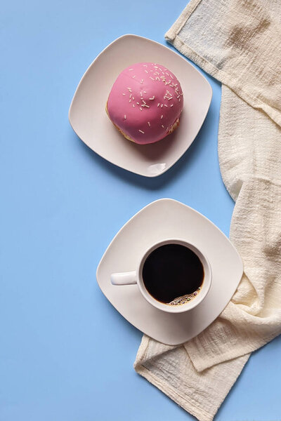 Утро с чашкой горячего кофе и сладкими пончиками на синем фоне. Букет тюльпанов. Вид сверху, место для копирования, макет. Плоский лежал. Еда и напитки. Весенние каникулы. 