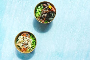 Tava kutusunun üst görüntüsü, siyah arka planda bir kase pirinç. Somon, avokado, soğan, mantar, brokoli ve susamlı pilav. Çin, Asya yemeği teslimatı. Tavalar için ambalaj. 