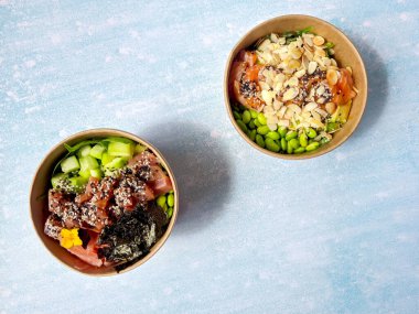 Tava kutusunun üst görüntüsü, siyah arka planda bir kase pirinç. Somon, avokado, soğan, mantar, brokoli ve susamlı pilav. Çin, Asya yemeği teslimatı. Tavalar için ambalaj. 