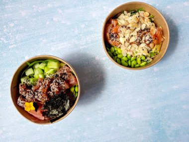 Tava kutusunun üst görüntüsü, siyah arka planda bir kase pirinç. Somon, avokado, soğan, mantar, brokoli ve susamlı pilav. Çin, Asya yemeği teslimatı. Tavalar için ambalaj. 