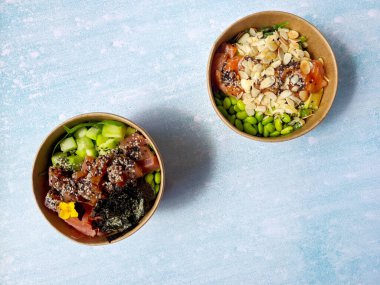 Tava kutusunun üst görüntüsü, siyah arka planda bir kase pirinç. Somon, avokado, soğan, mantar, brokoli ve susamlı pilav. Çin, Asya yemeği teslimatı. Tavalar için ambalaj. 