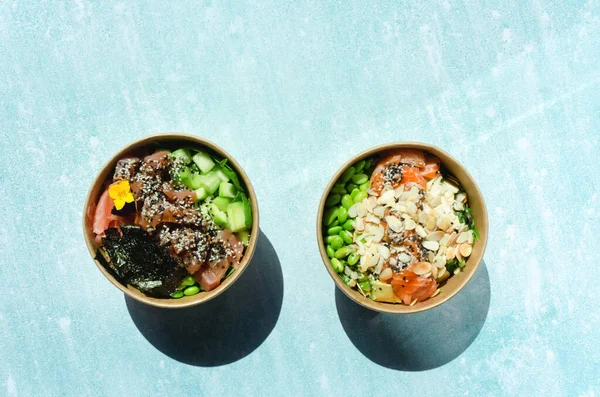 Tava kutusunun üst görüntüsü, siyah arka planda bir kase pirinç. Somon, avokado, soğan, mantar, brokoli ve susamlı pilav. Çin, Asya yemeği teslimatı. Tavalar için ambalaj. 