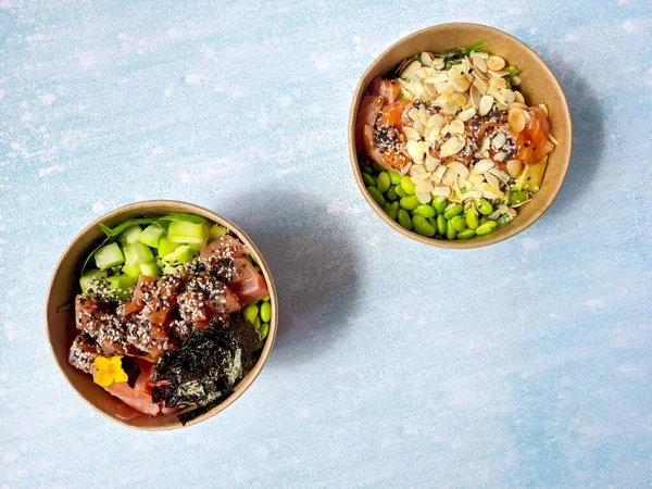 Tava kutusunun üst görüntüsü, siyah arka planda bir kase pirinç. Somon, avokado, soğan, mantar, brokoli ve susamlı pilav. Çin, Asya yemeği teslimatı. Tavalar için ambalaj. 