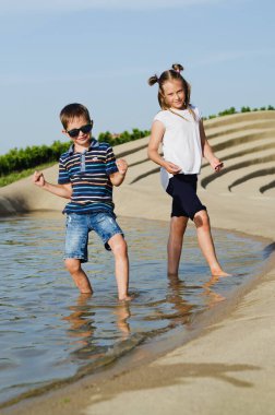 Mutlu aile hayatı ve tatil konsepti. Anne, küçük oğlan, kız oturuyor, eski şehirde, sokakta yürüyor. Mobiletlere bin. Güneşli bir yaz gününde gülüyorlar. Eğleniyorum.