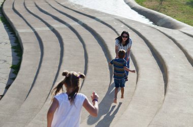 Mutlu aile hayatı ve tatil konsepti. Anne, küçük oğlan, kız, scooter 'a biniyor, eski şehirde, sokakta yürüyor. - Dondurma. Güneşli bir yaz gününde gülüyorlar. Eğleniyorum.