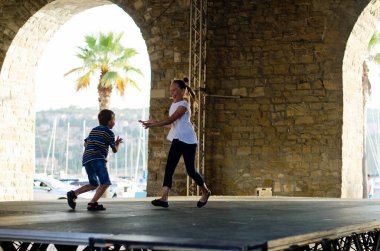 Mutlu aile hayatı ve tatil konsepti. Anne, küçük oğlan, kız, scooter 'a biniyor, eski şehirde, sokakta yürüyor. - Dondurma. Güneşli bir yaz gününde gülüyorlar. Eğleniyorum.