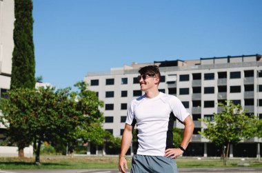 Genç, mutlu, sakallı adam, parkta oturan bir turist. Gülümsüyor, rahatlıyor. Yaz tatili. Güneş gözlüğü. Yaşam tarzı portresi. 