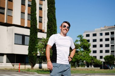 Genç, mutlu, sakallı adam, parkta oturan bir turist. Gülümsüyor, rahatlıyor. Yaz tatili. Güneş gözlüğü. Yaşam tarzı portresi. 