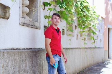 Genç, mutlu, sakallı adam, parkta oturan bir turist. Gülümsüyor, rahatlıyor. Yaz tatili. Güneş gözlüğü. Yaşam tarzı portresi. 