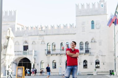 Koper, Slovenya. 25.06.2022. Genç ve yakışıklı sakallı adam, eski Koper şehrinde yürüyen bir turist. Yaz tatili. Güneş gözlüğü. Yaşam tarzı portresi