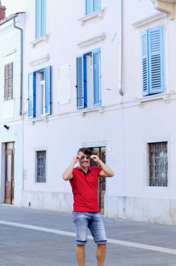 Koper, Slovenya. 25.06.2022. Genç ve yakışıklı sakallı adam, eski Koper şehrinde yürüyen bir turist. Yaz tatili. Güneş gözlüğü. Yaşam tarzı portresi