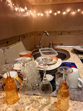 Dirty and unwashed dishes standing on the table in a kitchen at home. Cups of coffee, plates, spoons, forks are in the sink