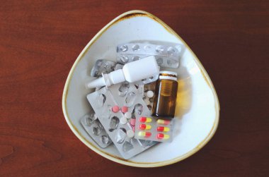 Bir sürü hap, burun damlası, paketler ve tabakta haplarla birlikte kabarcıklar var. Sağlık sigortası, tıp endüstrisi. Sağlıklı yaşam tarzı