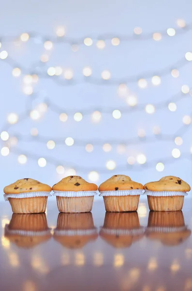 Christmas sweet cupcakes against white background with bokeh lights. New year celebration. Food.