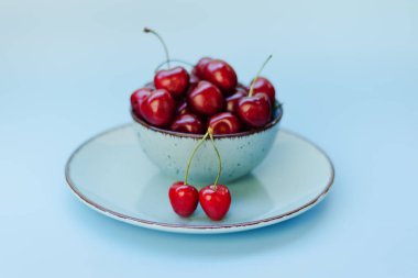 Mavi tabakta kırmızı kirazlı üst manzara. Vegan, yaz yemeği konsepti. Diyet