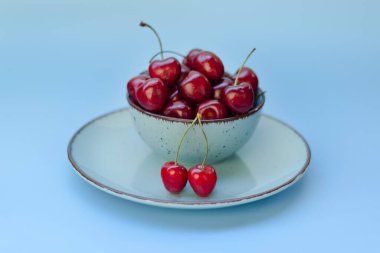 Mavi tabakta kırmızı kirazlı üst manzara. Vegan, yaz yemeği konsepti. Diyet