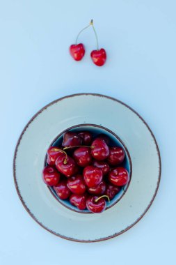 Mavi tabakta kırmızı kirazlı üst manzara. Vegan, yaz yemeği konsepti. Diyet