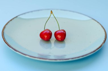 Mavi tabakta kırmızı kirazlı üst manzara. Vegan, yaz yemeği konsepti. Diyet