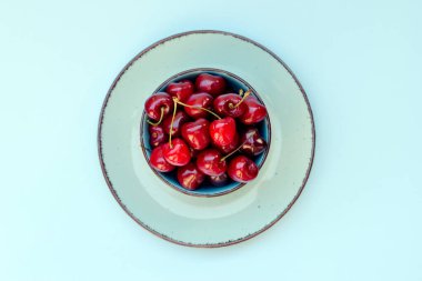 Mavi tabakta kırmızı kirazlı üst manzara. Vegan, yaz yemeği konsepti. Diyet