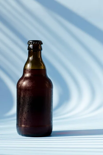 Top view of glass brown beer bottle, glass of beer against blue background close up. Food lifestyle. Alcoholic drink production. Copy space, mockup.