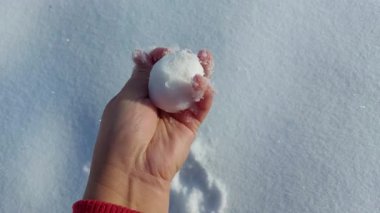 Çıplak elle kar topu tutan bir kadın.