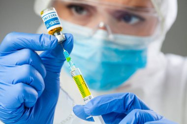 COVID-19 aşısı, Coronavirus aşısı konsepti, mavi eldivenli doktorun elleri ilaç şişesi ve şırınga taşıyor, SARS-CoV-2 aşısı, virüs tedavisinin araştırılması ve geliştirilmesi