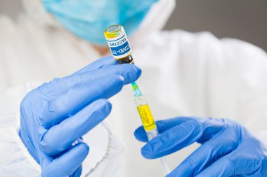 İlaç, aşı ve sağlık sigortası konsepti, koruyucu tıbbi maske takan doktor şırıngayı COVID-19 aşısı ile dolduruyor, NHS araştırmacısı eldiven içinde tedavi aşısı tutuyor.