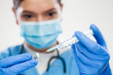 Kadın NHS çalışanı cam ampulden aşı aşısı alıyor, şırıngaya iğne batırıyor, Coronavirus aşısı hazırlığı yapıyor, COVID-19 aşılama, önleme ve koruma