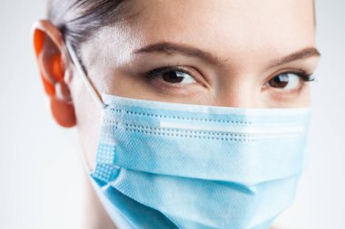 Kafkasyalı güzel bir kadının koruyucu yüz maskesi takan portresi, kahverengi göz detayı, beyaz arka planda izole edilmiş, COVID-19 Coronavirus hastalığı enfeksiyonuna karşı pandemik tedbirler