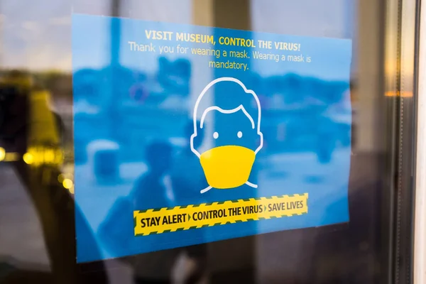 Blue sign on museum window or glass door informing visitors that wearing protective face mask indoor is mandatory,STAY ALERT - CONTROL THE VIRUS - SAVE LIVES concept,safety regulations during COVID-19