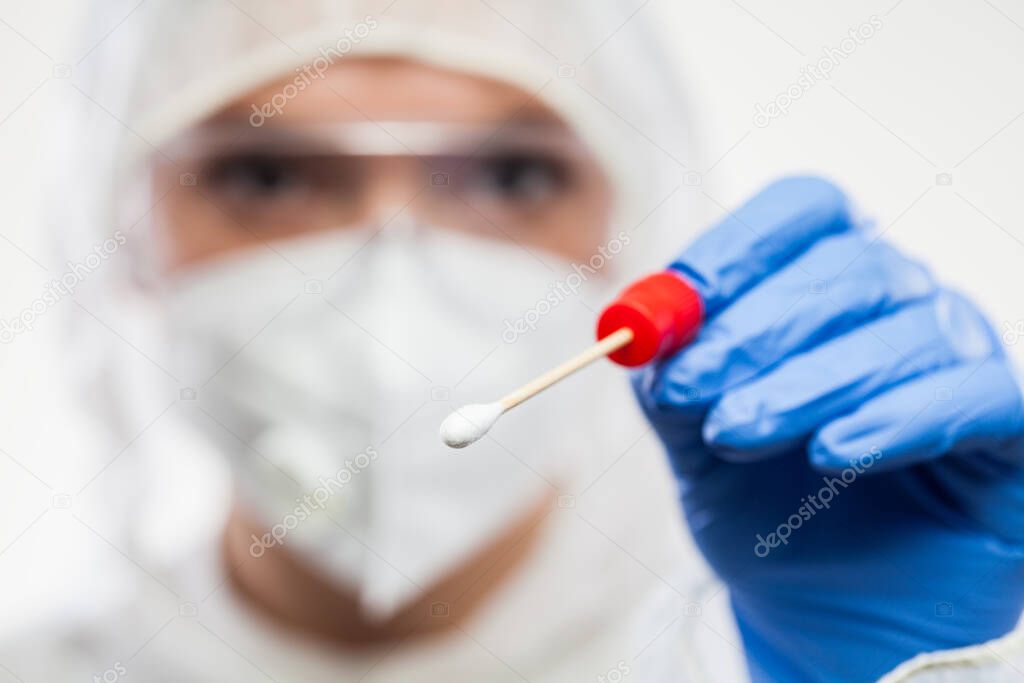 Female medical worker holding cotton swab sample stick for collecting nasal or oral patient specimen sample,nose or throat examination for detecting Coronavirus presence,PCR COVID-19 testing process