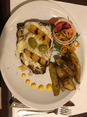 MALTA, 9 Mart 2020 Eritilmiş peynirli biftek ve beyaz tabakta patates.